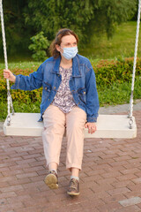 Woman in a medical mask rides a street swing