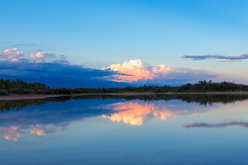 Beautiful sunset by the lake. Bright clouds are reflected in the water. Kyrgyzstan.