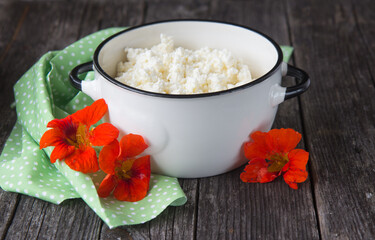 Homemade cottage cheese in a white cup and fresh marigold flowers on a green napkin.