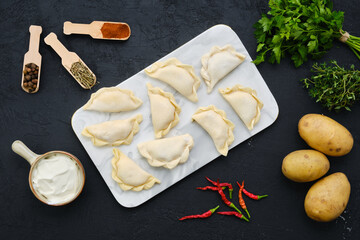 Top view of potato vareniki on marble serving board with ingredients