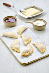 Cherry vareniki on marble serving board with ingredients