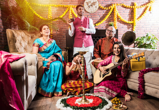 Happy Indian Family Singing, Playing Music, Guitar While Celebrating Festivals In Traditional Cloths