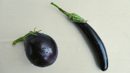 Ripe whole black eggplants on a white background