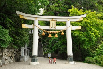 Shrine white and gold big gate called "Torii" . Japanese text on gate is "Hotosan Jinja Shrine (Shrine name)". At Chichibu, Saitama, Japan.