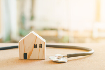 Home repair and inspector concept. Stethoscope and wooden home model. Checking house and real estate with sunlight.