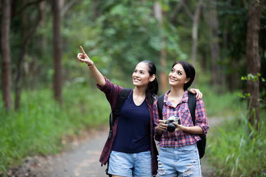 Asian Group of young people Hiking with friends backpacks walking together and looking map and taking photo camera by the road and looking happy ,Relax time on holiday concept travel