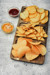 Chips, snacks and crackers on a wooden board. Fast food.