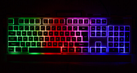 Fototapeta premium Laptop gamer keyboard with pink yellow and light blue buttons on black background. light, rgb, led