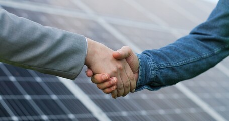 Close up view of shaking hands after discussion on background of photovoltaic solar panels. © VAKSMANV