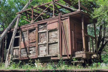 Old abandoned rusty wooden train and cargo wagon on the railway in the forest