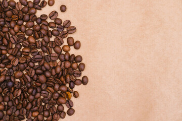 Coffee bean background. Dark roasted coffee beans are scattered on the Kraft paper.