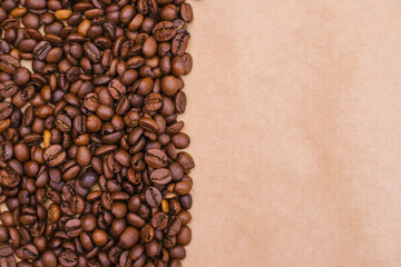Coffee bean background. Dark roasted coffee beans are scattered on the Kraft paper.