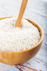 Fototapeta na wymiar Wooden bowl full of basmati rice on wooden background.