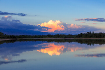 Beautiful sunset by the lake. Bright clouds are reflected in the water. Kyrgyzstan.