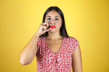 Young beautiful woman over isolated yellow background mouth and lips shut as zip with fingers. Secret and silent, taboo talking