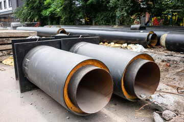 Closeup view of two new insulated water pipes on city road in summer day. Urban sewerage...