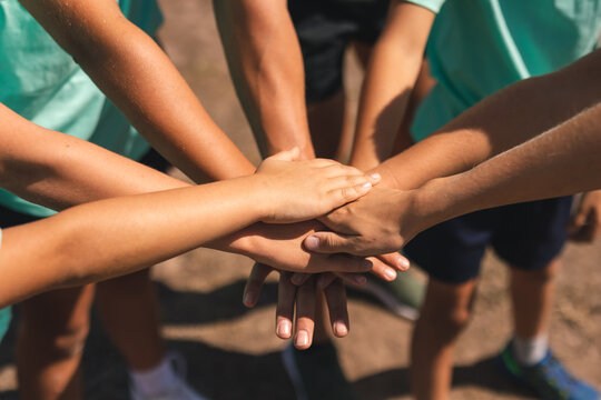 Mid section of group of kids stacking hands together