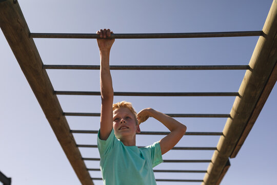 Boy hanging on monkey bars at a boot camp - Powered by Adobe