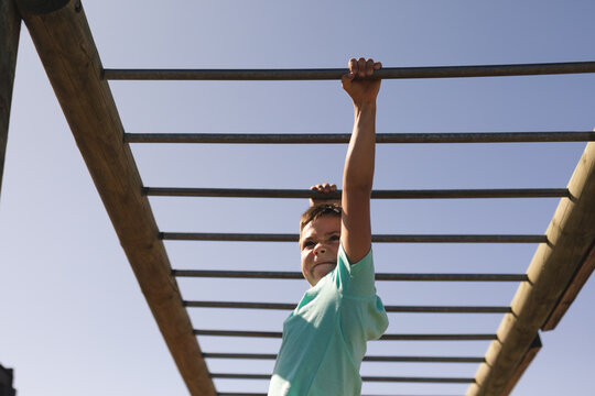 Boy hanging on monkey bars at a boot camp - Powered by Adobe