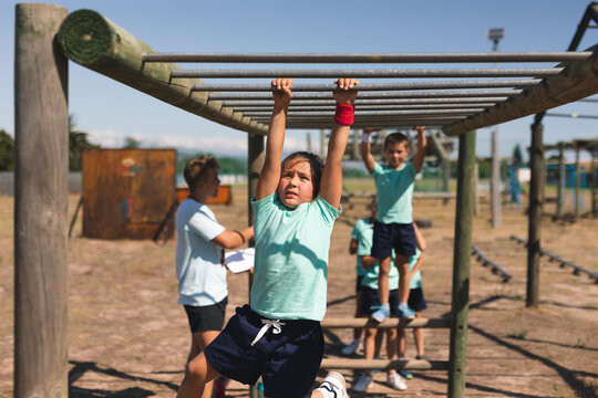 Boy hanging on monkey bars at a boot camp - Powered by Adobe