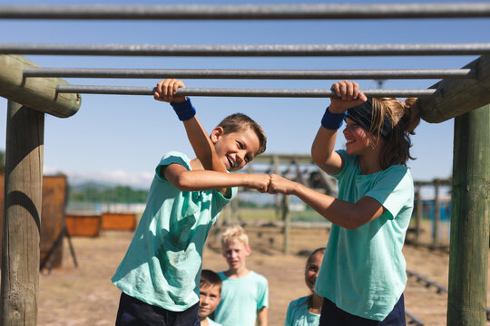 Two boys doing a fist bump while hanging on monkey bars at a bootcamp - Powered by Adobe