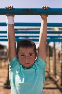 Portrait of boy hanging on monkey bars at a boot camp
