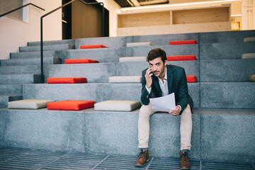 Fototapeta na wymiar Portrait of South Asian entrepreneur holding financial report with corporate statistics and making smartphone call for discussing details, formally dressed businessman phoning via cellphone app