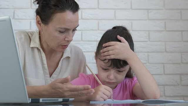 Mother argue with pupil. A mother helps her little daughter do her homework. Quarantine education concept.