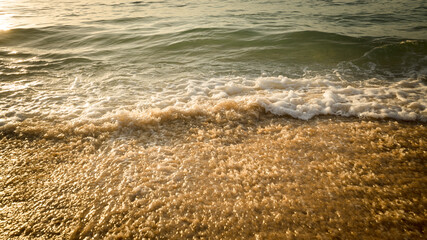 Scenic seascape. Milky foam waves at the beach. Sunset time. Waterscape for background. Selected soft art focus. Sunlight reflection on the water and sand. Balangan beach, Bali, Indonesia