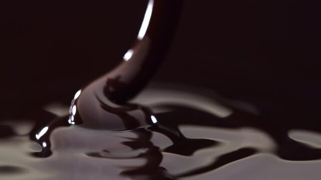 Slow motion of pouring melted dark chocolate.