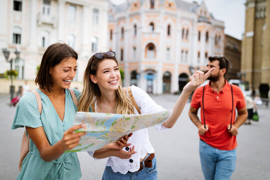 Happy traveling tourists sightseeing with map and having fun