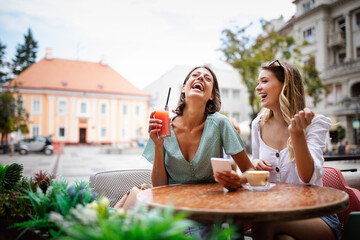Technology, friendship and people concept. Happy young women with smartphone at outdoor cafe