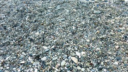 Stony beach on a sunny day. Background of different pebbles from above on the beach