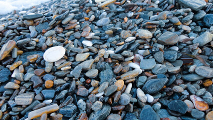 Stony beach on a sunny day. Background of different pebbles from above on the beach
