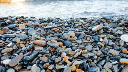 Stony beach on a sunny day. Background of different pebbles from above on the beach