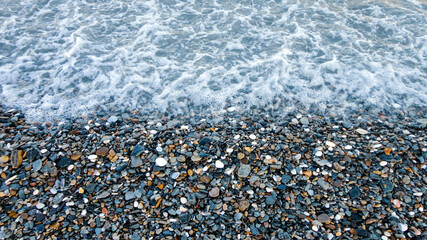 Stony beach on a sunny day. Background of different pebbles from above on the beach