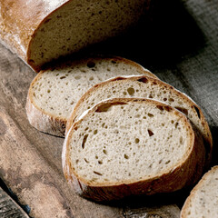 Sliced whole grain artisan rye-wheat organic bread over old wooden background. Close up
