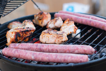 Assortment of marinated meat grilling over the hot coals on a BBQ with sausage, steak, chicken, spare ribs and kebabs with copy space