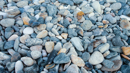 Stony beach on a sunny day. Background of different pebbles from above on the beach