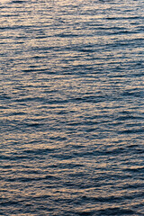 The sea at sunset in shallow wind with a small rippled surface in orange and blue evening light