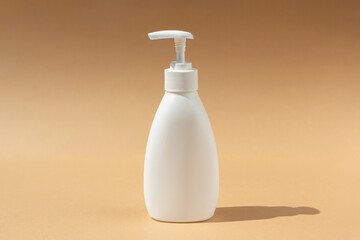 white dispenser bottle, for spa cosmetic products on a beige background.