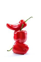 Tower of three red pepper isolated on white background. Two sweet bell peppers and one capsicum hot chili arranged one on one. Close up, copy space. Healthy food concept. Vegetable stacked vertically.