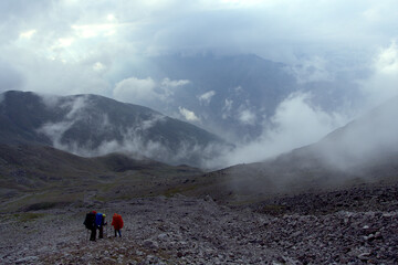 Tourists hike through the valley. View from the Kashtan Pass, Caucasus, Russia. Height 3513 meters above sea level.