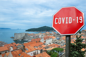 COVID-19 sign against view from above of red roofs and city wall in Dubrovnik, Croatia. Warning about pandemic in Croatia. Coronavirus disease. COVID-2019 alert sign