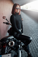 Obraz na płótnie Canvas Redhead sexual female rider sitting on modern bike