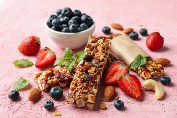 Granola bars and bowl with blueberry on pink background, closeup