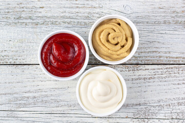 Set of three kinds of classic sauces on wooden background. Mayonnaise ketchup mustard