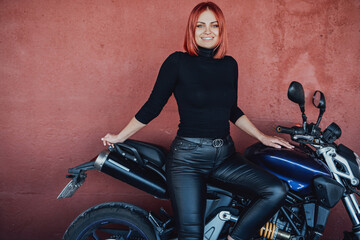 An attractive girl with red hairs sitting on her urban bike