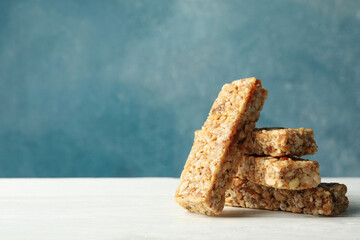 Tasty granola bars on white wooden table against blue background