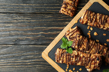 Board with granola bars on wooden background, top view